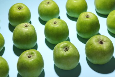 Photo of Ripe green apples on light blue background, closeup