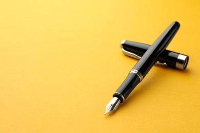 Photo of Stylish fountain pen with cap on yellow background. Space for text