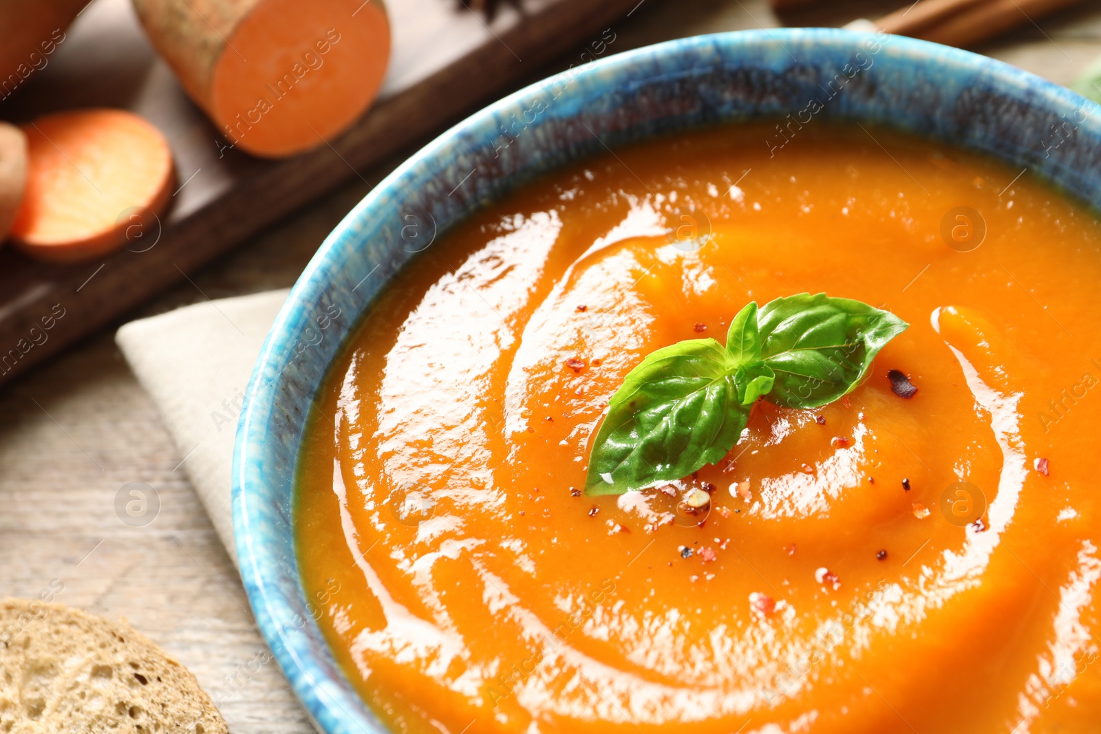 Photo of Bowl of tasty sweet potato soup on table, closeup. Space for text