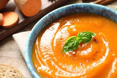 Bowl of tasty sweet potato soup on table, closeup. Space for text