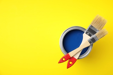 Open cans with paint and brushes on color background, top view. Space for text