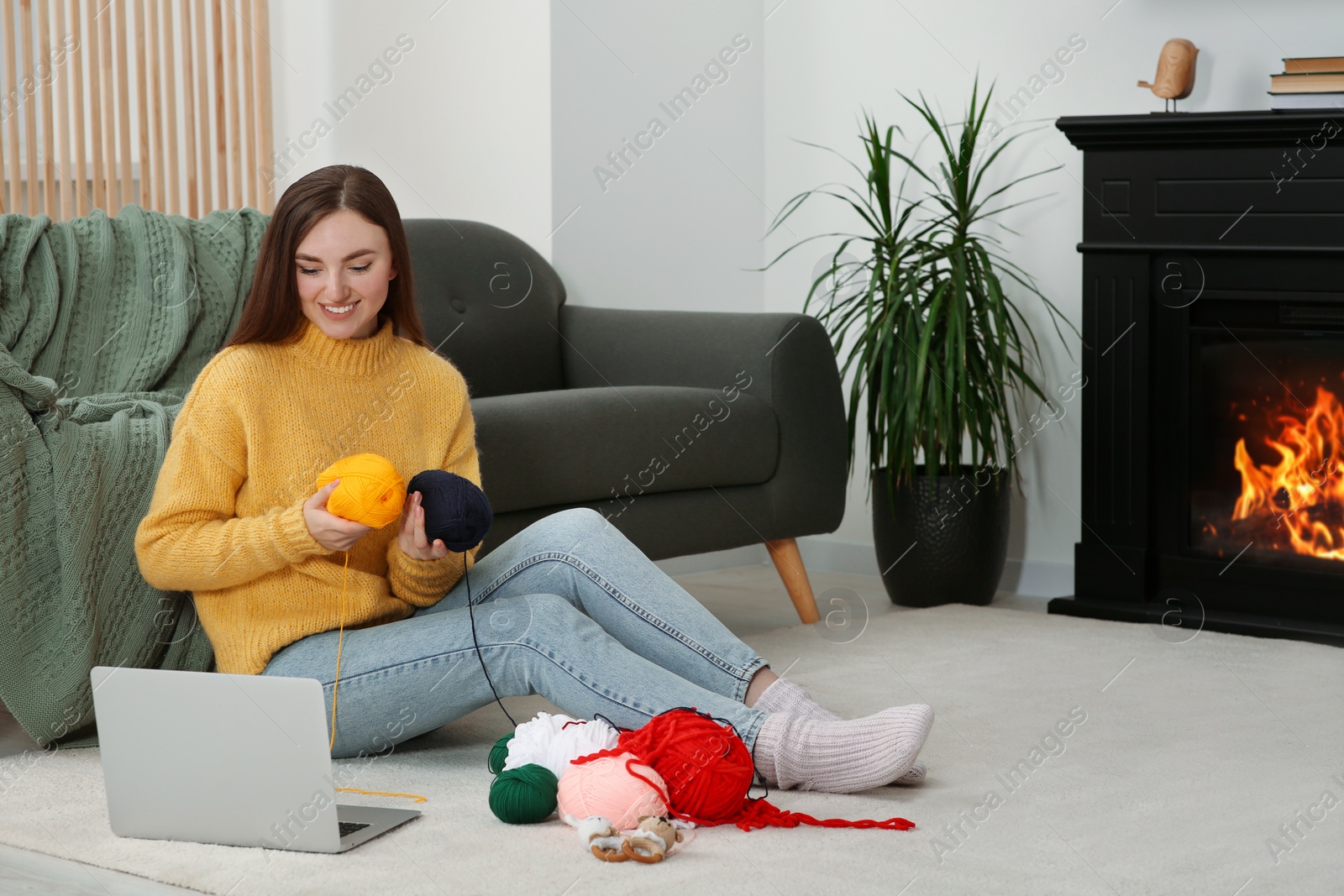 Photo of Young woman learning to knit with online course at home, space for text. Handicraft hobby