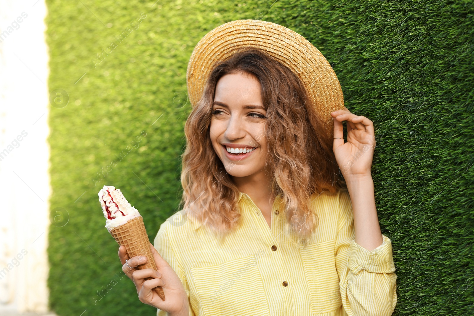 Photo of Happy young woman with delicious ice cream in waffle cone outdoors