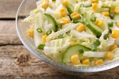 Photo of Tasty salad with Chinese cabbage, corn and cucumber in bowl on wooden table, closeup