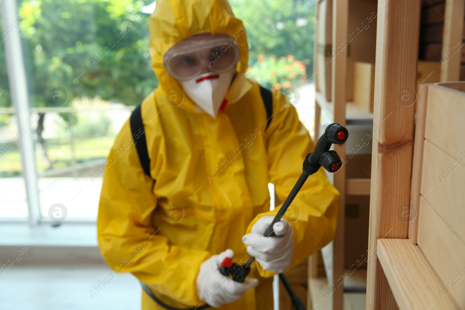 Photo of Pest control worker spraying pesticide indoors, focus on nozzle