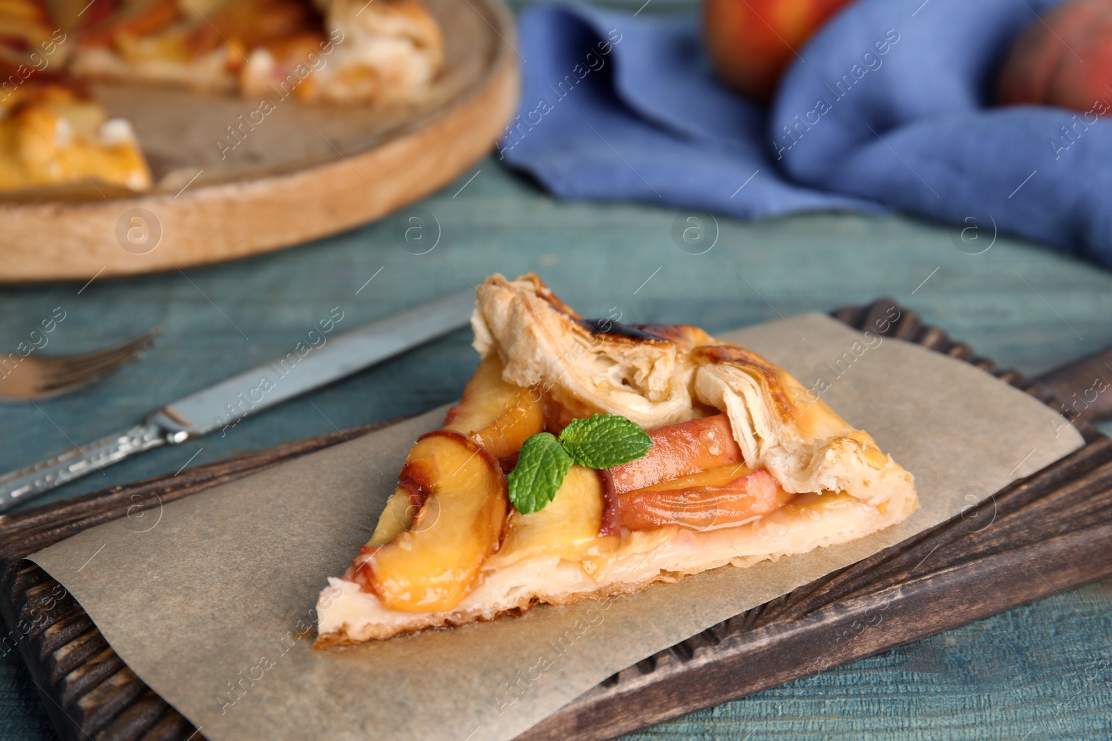 Photo of Piece of delicious fresh peach pie on blue wooden table, closeup