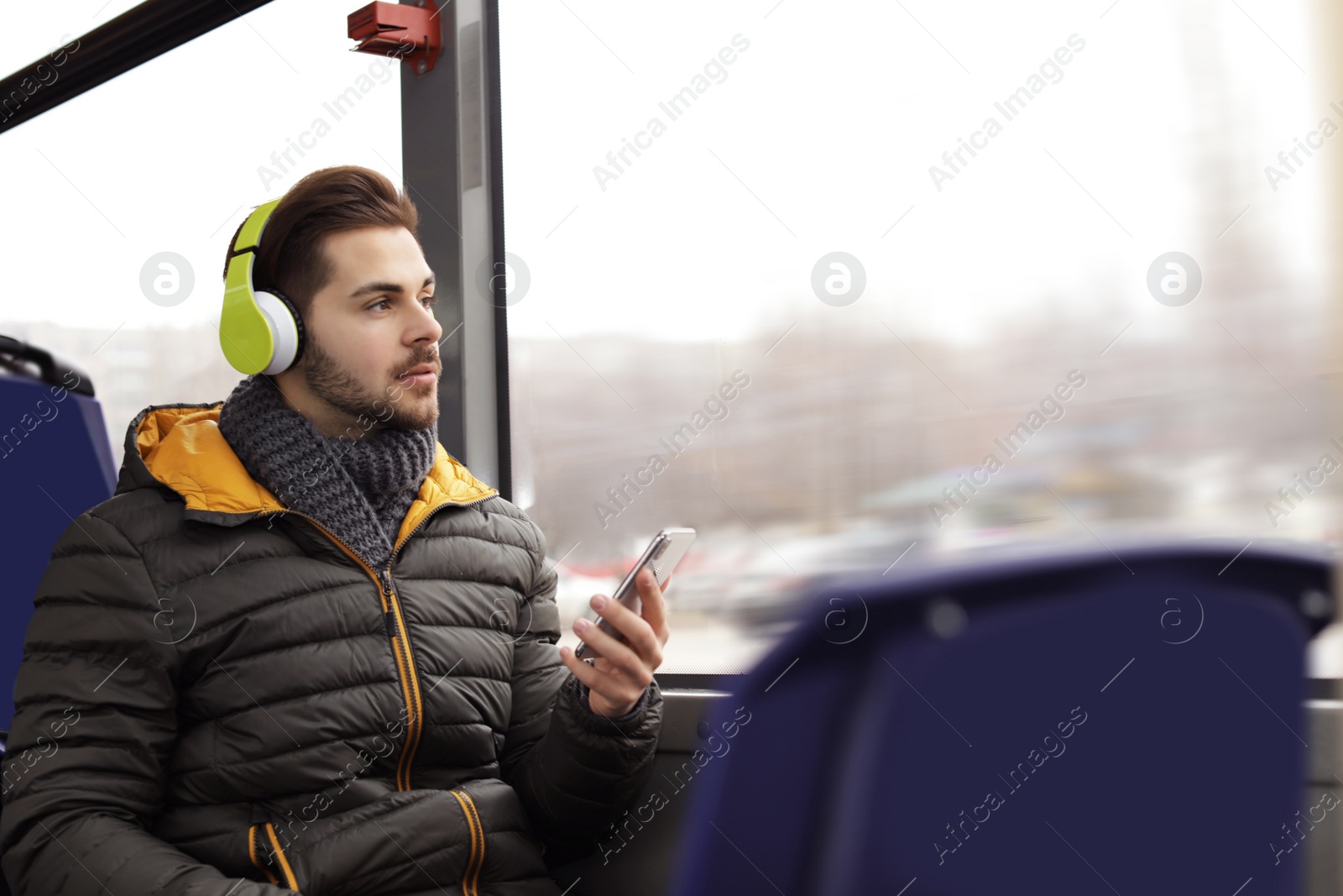 Photo of Young man listening to music with headphones in public transport