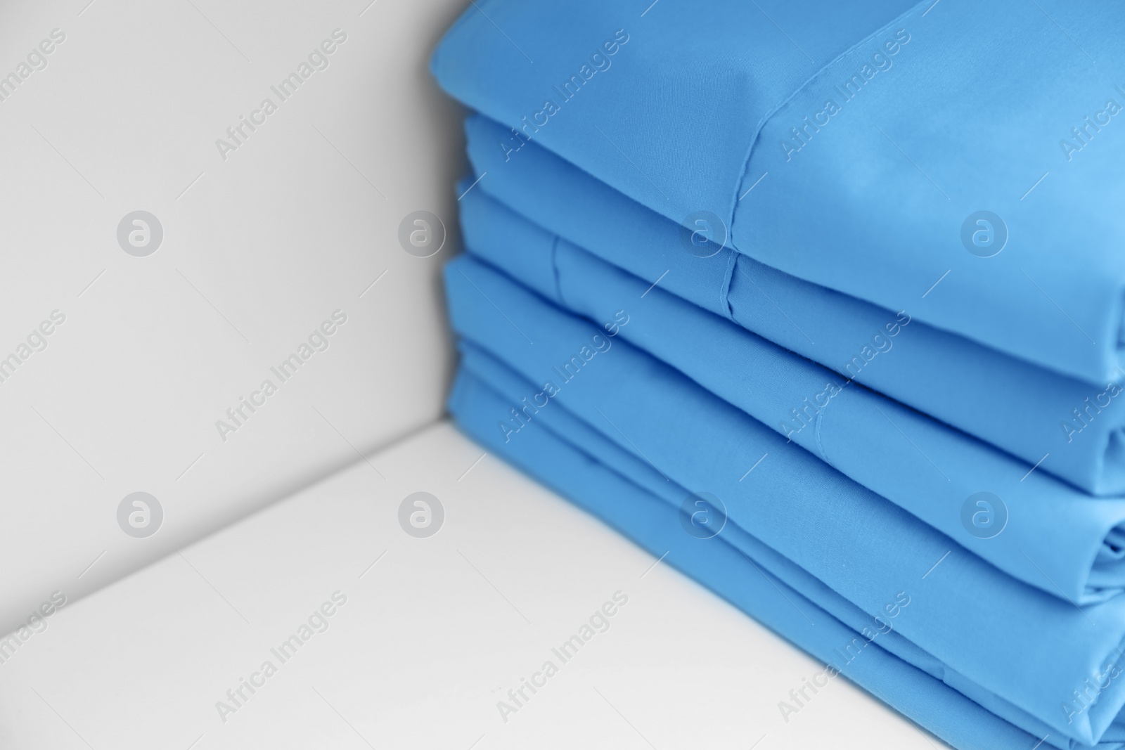 Photo of Light blue medical uniforms on white rack, closeup. Space for text