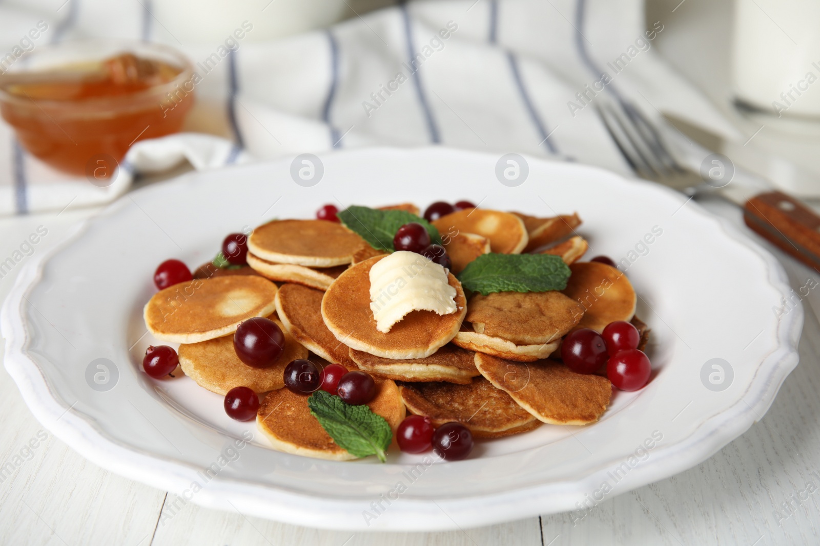 Photo of Cereal pancakes with cranberries and butter on white wooden table