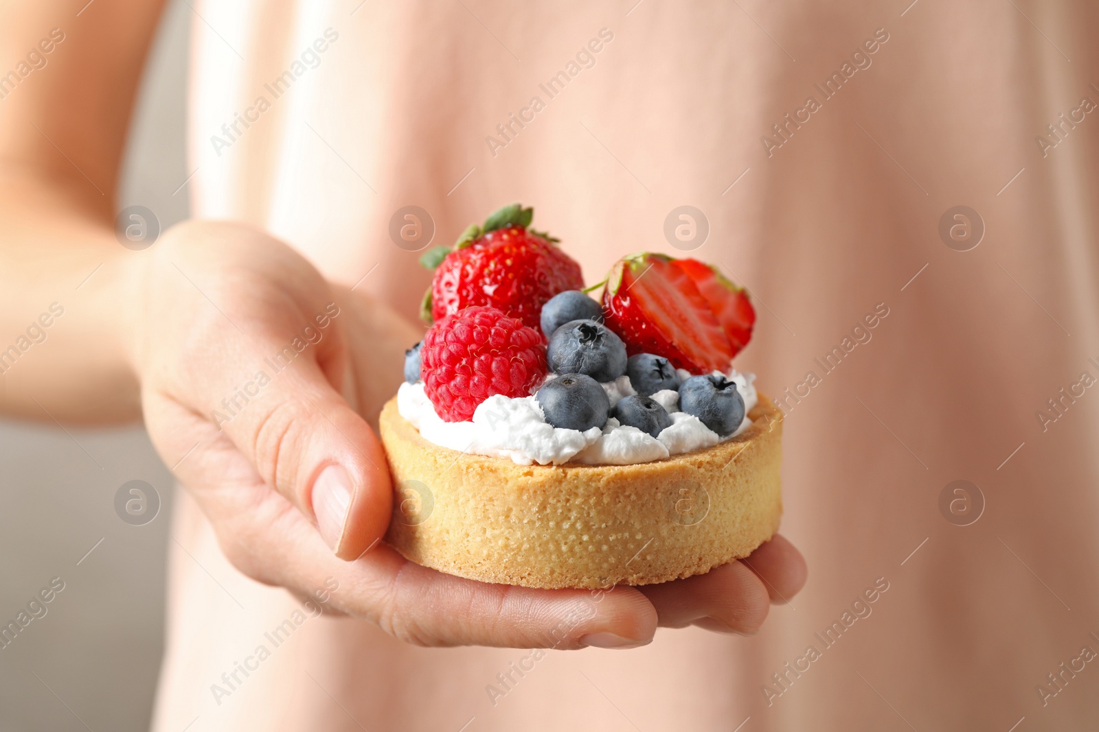 Photo of Woman holding tart with different berries, closeup. Delicious pastries