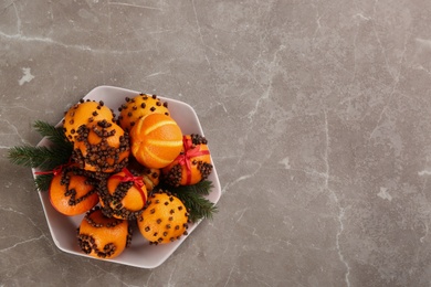 Pomander balls made of fresh tangerines and cloves on grey table, top view. Space for text