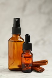 Photo of Bottles of organic cosmetic products and cinnamon sticks on grey marbled background