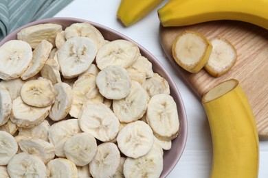 Photo of Freeze dried and fresh bananas on white wooden table, flat lay