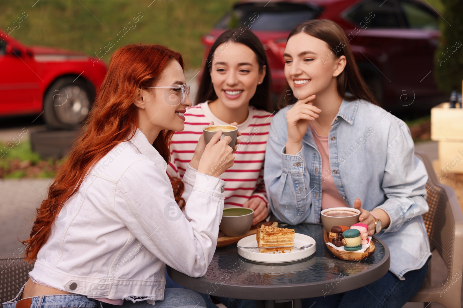 Photo of Happy friends talking and drinking coffee in outdoor cafe