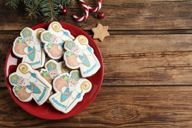 Photo of Tasty gingerbread cookies and festive decor on wooden table, flat lay with space for text. St. Nicholas Day celebration
