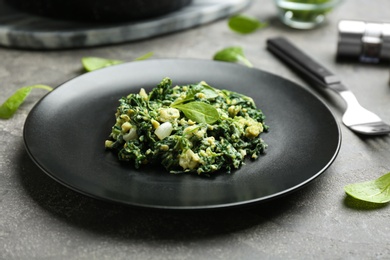 Photo of Plate with tasty spinach on grey table, closeup. Healthy food