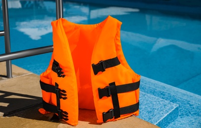 Photo of Bright orange life jacket near swimming pool