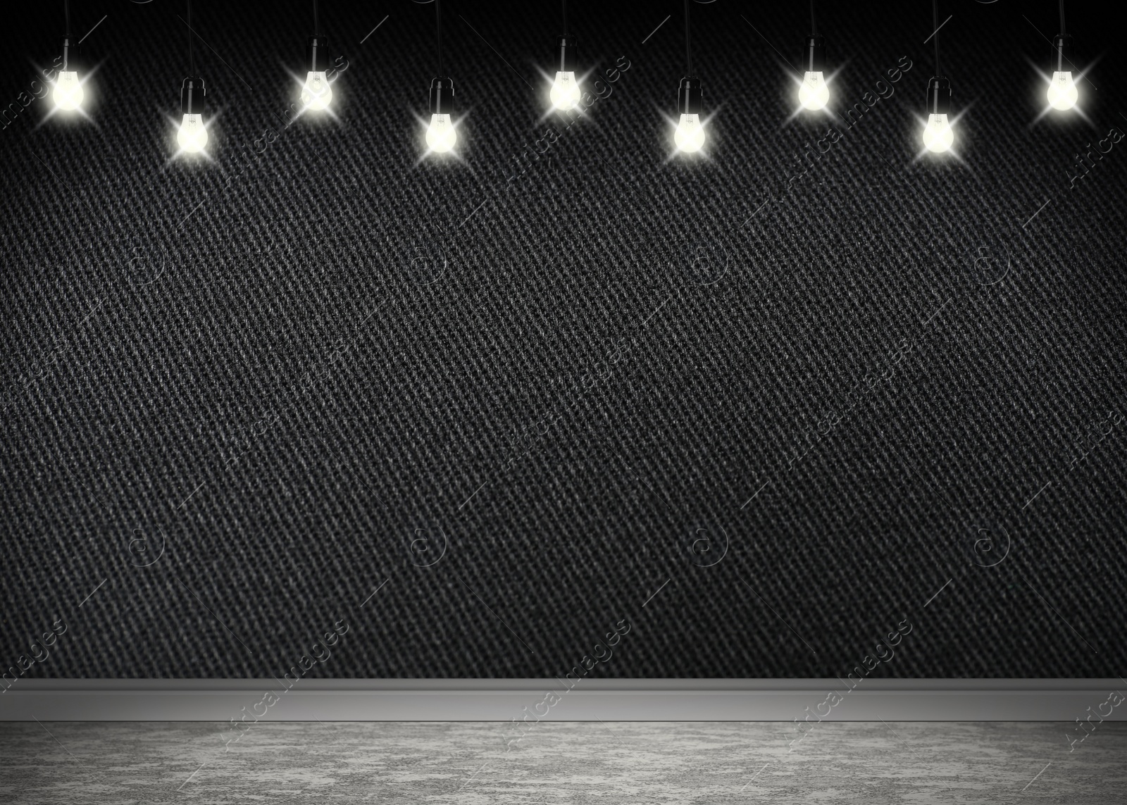 Image of Glowing light bulbs in room with black wall and grey floor