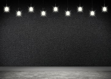 Glowing light bulbs in room with black wall and grey floor