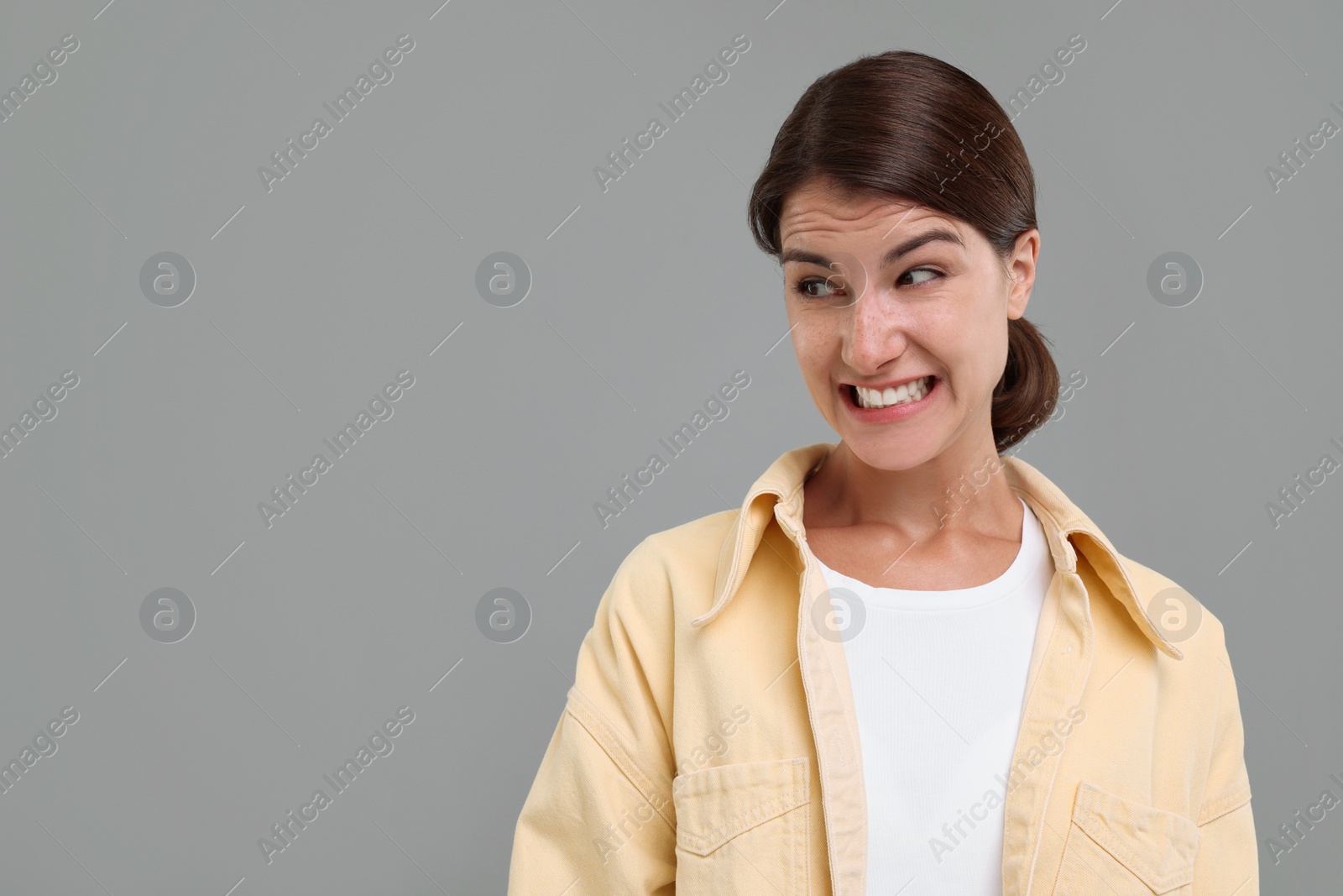 Photo of Portrait of embarrassed young woman on grey background, space for text