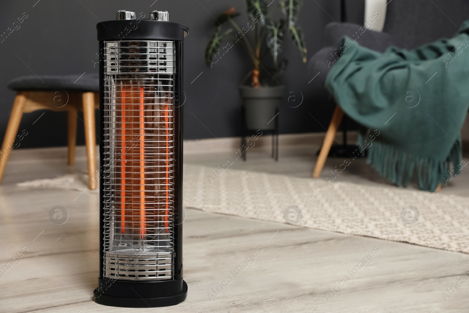 Photo of Modern electric halogen heater on floor in room interior