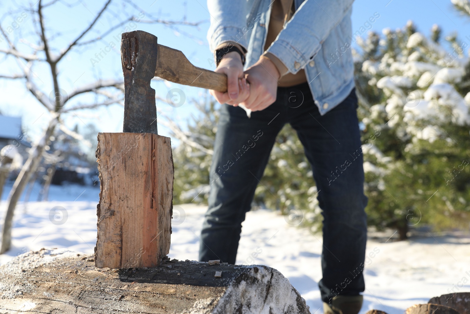 Photo of Man chopping wood with axe outdoors on winter day, closeup