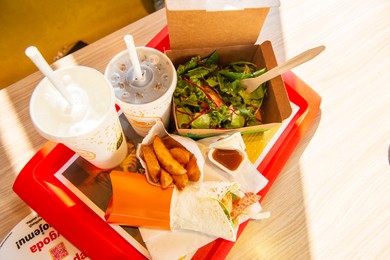 Photo of WARSAW, POLAND - SEPTEMBER 16, 2022: Big Mac hamburger, fried potatoes and cold drinks on table in McDonald's cafe, above view