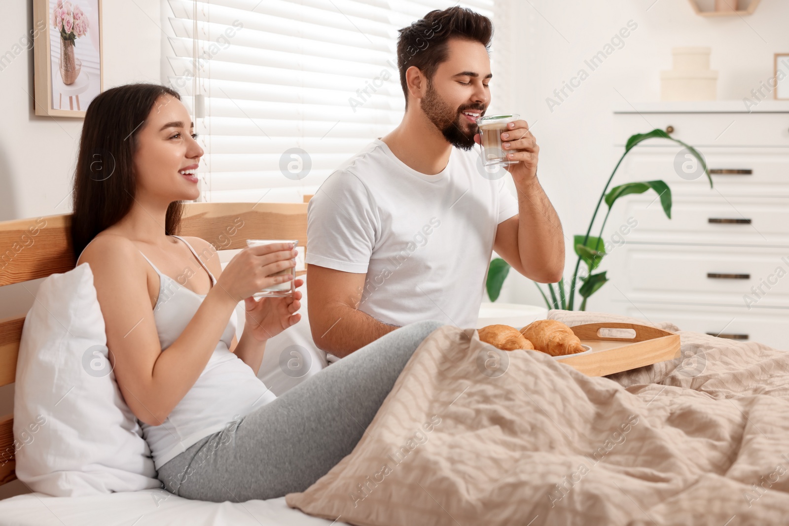 Photo of Happy couple having breakfast on bed at home