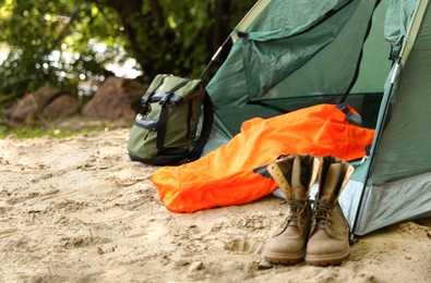 Photo of Camping tent with sleeping bag, boots and backpack on beach