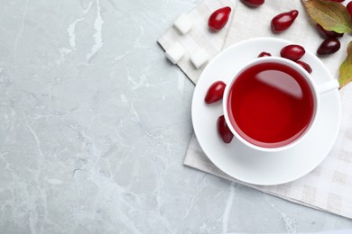 Cup of fresh dogwood tea and berries on light grey table, flat lay. Space for text