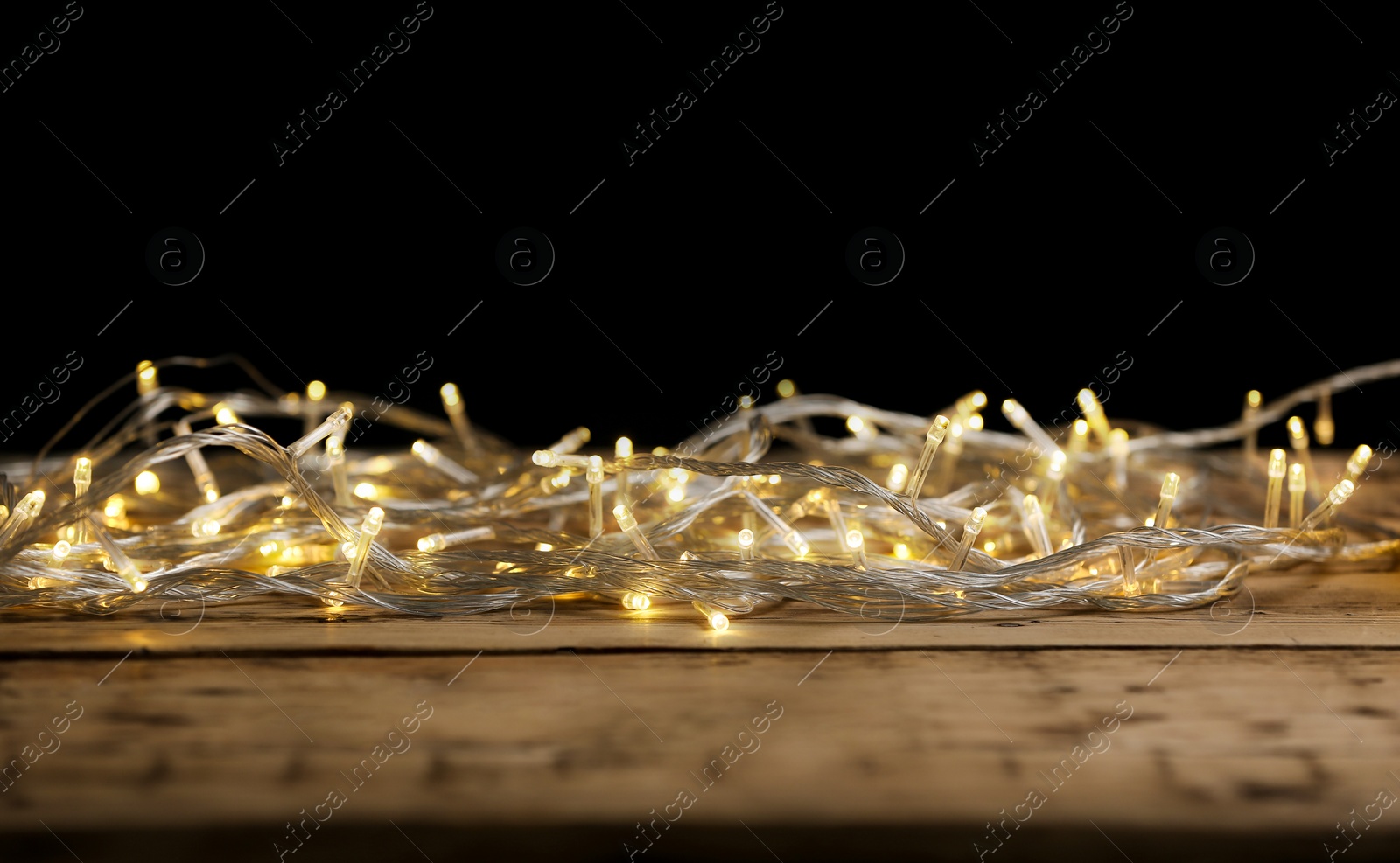 Photo of Yellow Christmas lights on wooden table against black background