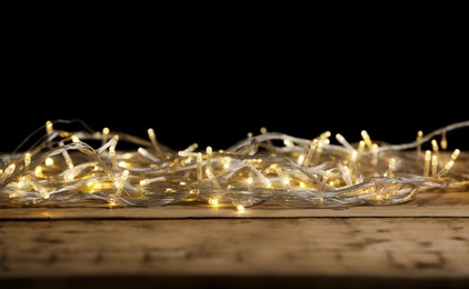 Photo of Yellow Christmas lights on wooden table against black background