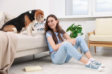 Photo of Happy young woman with her cute Beagle dog at home. Lovely pet