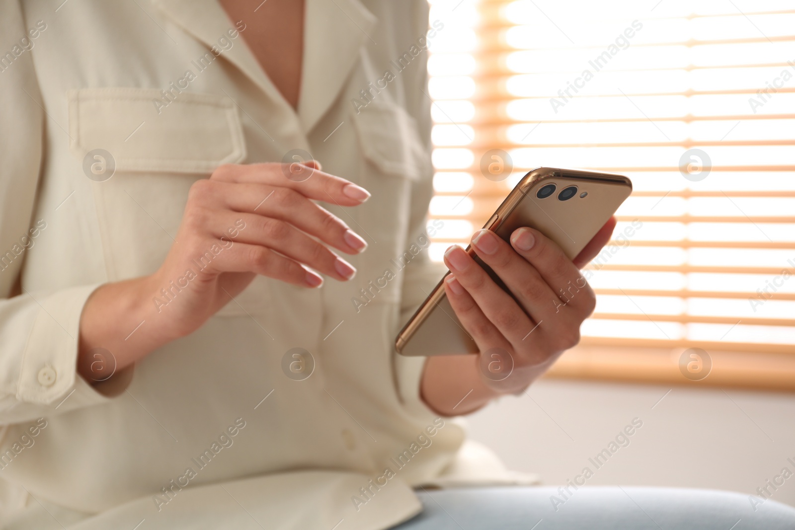 Photo of Young woman using modern smartphone indoors, closeup