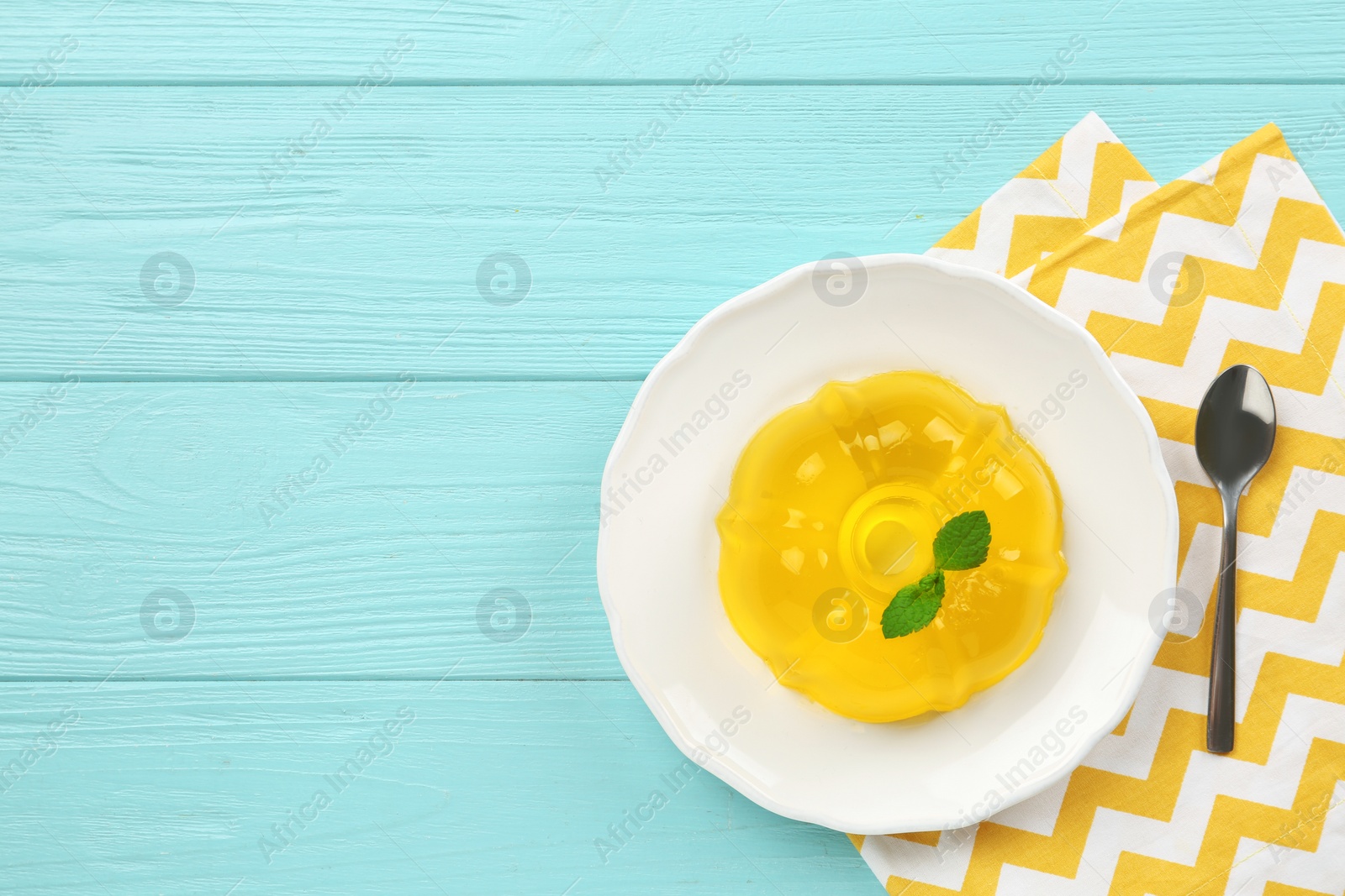 Photo of Plate of tasty fruit jelly served on blue wooden table, flat lay with space for text