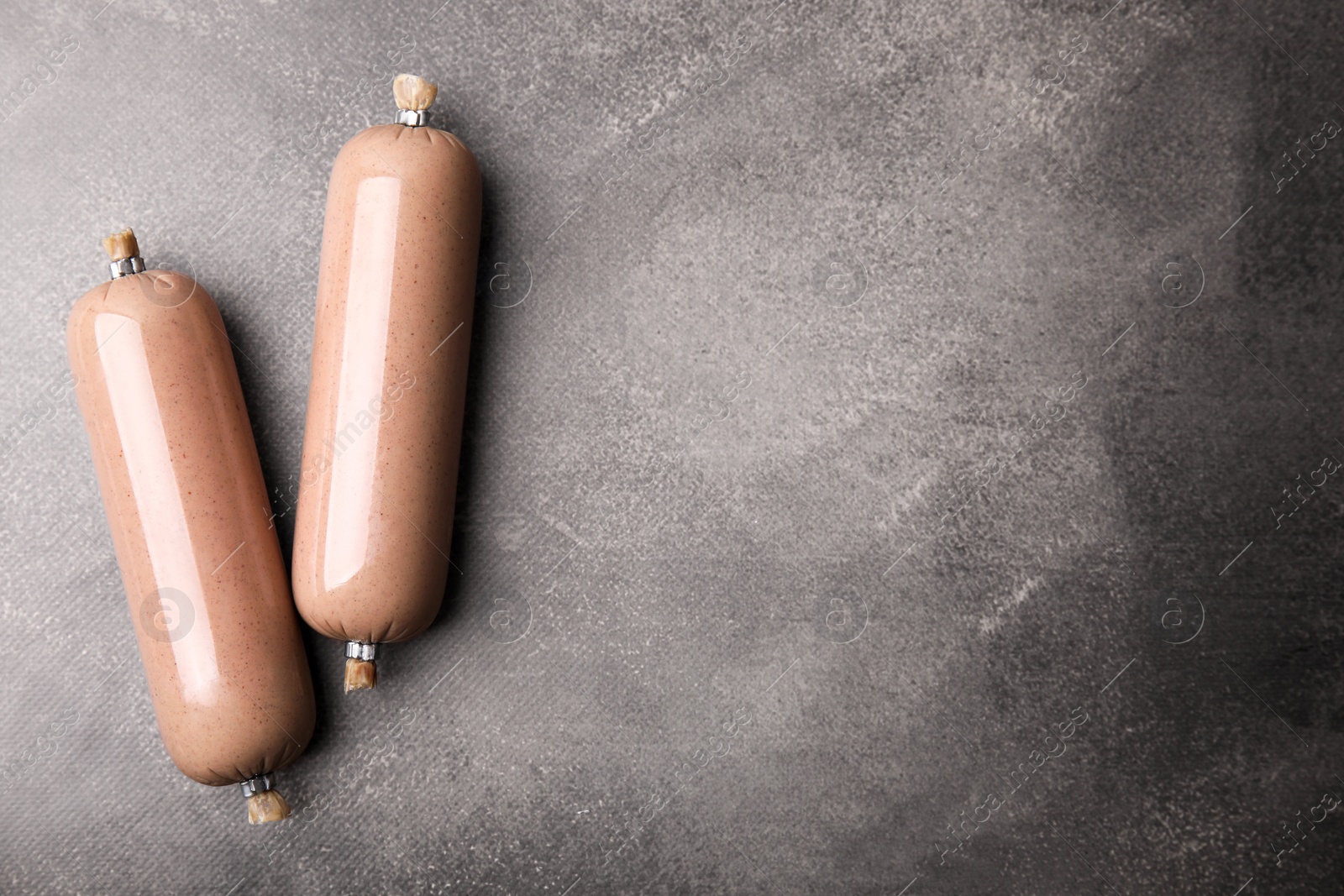 Photo of Delicious liver sausages on grey table, flat lay. Space for text