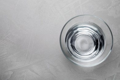 Glass bowl with water on grey table, top view. Space for text