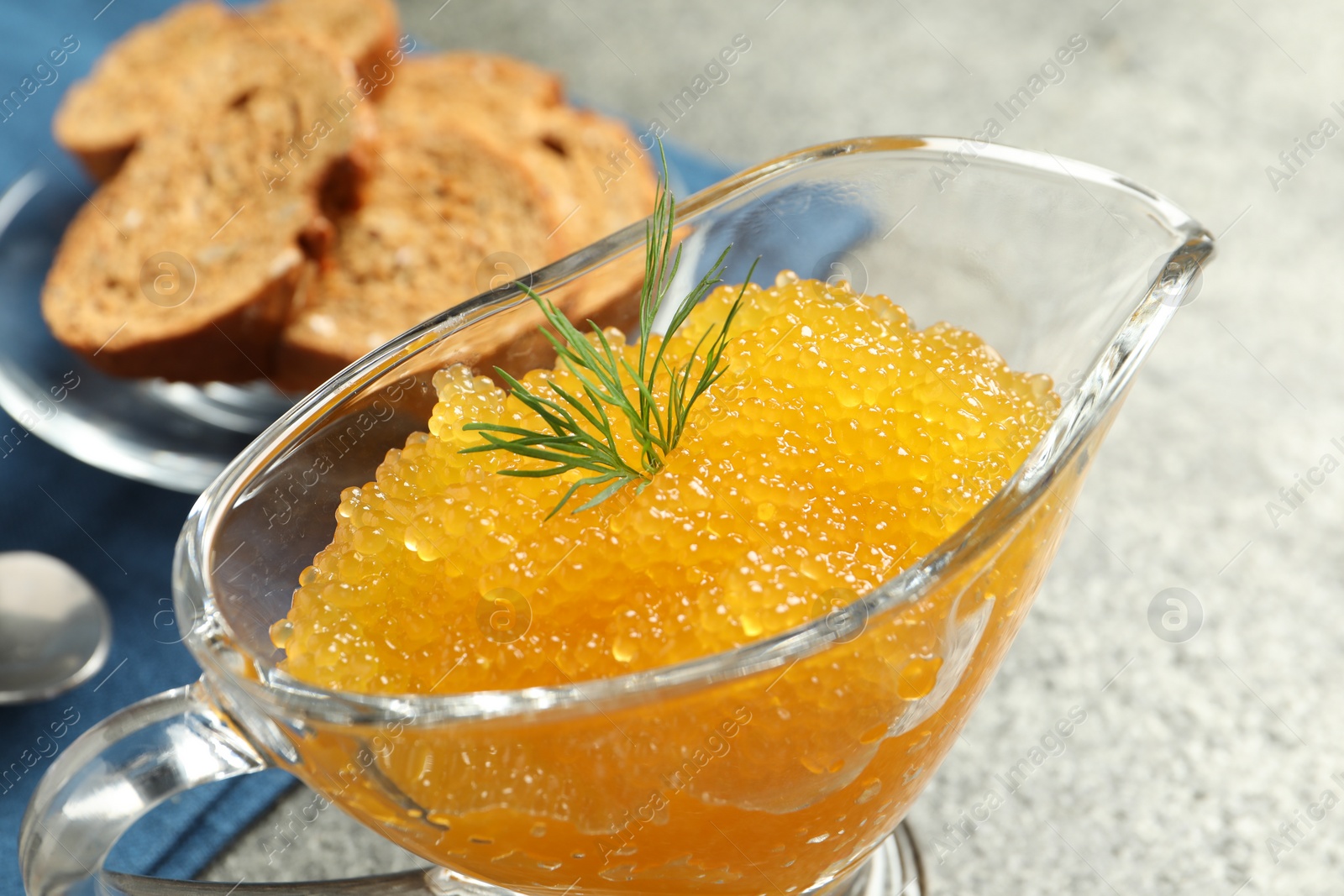 Photo of Fresh pike caviar and dill in gravy boat on grey table, closeup