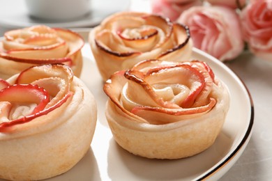 Freshly baked apple roses on light table, closeup. Beautiful dessert