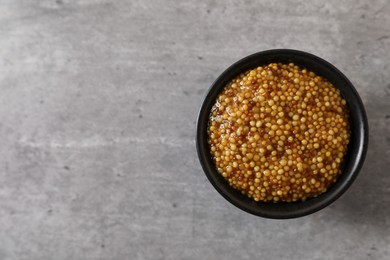 Photo of Bowl of whole grain mustard on grey table, top view. Space for text