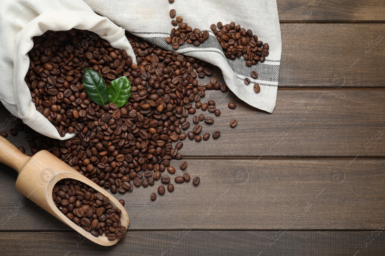 Photo of Scoop and bag with roasted coffee beans on wooden table, flat lay. Space for text