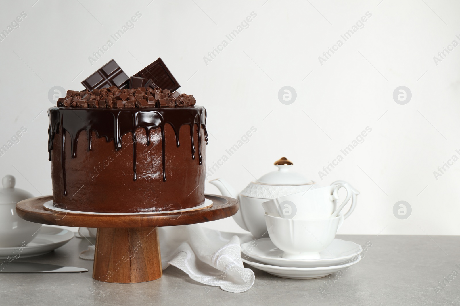 Photo of Freshly made delicious chocolate cake on grey table against white background. Space for text