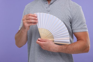 Photo of Man holding hand fan on purple background, closeup