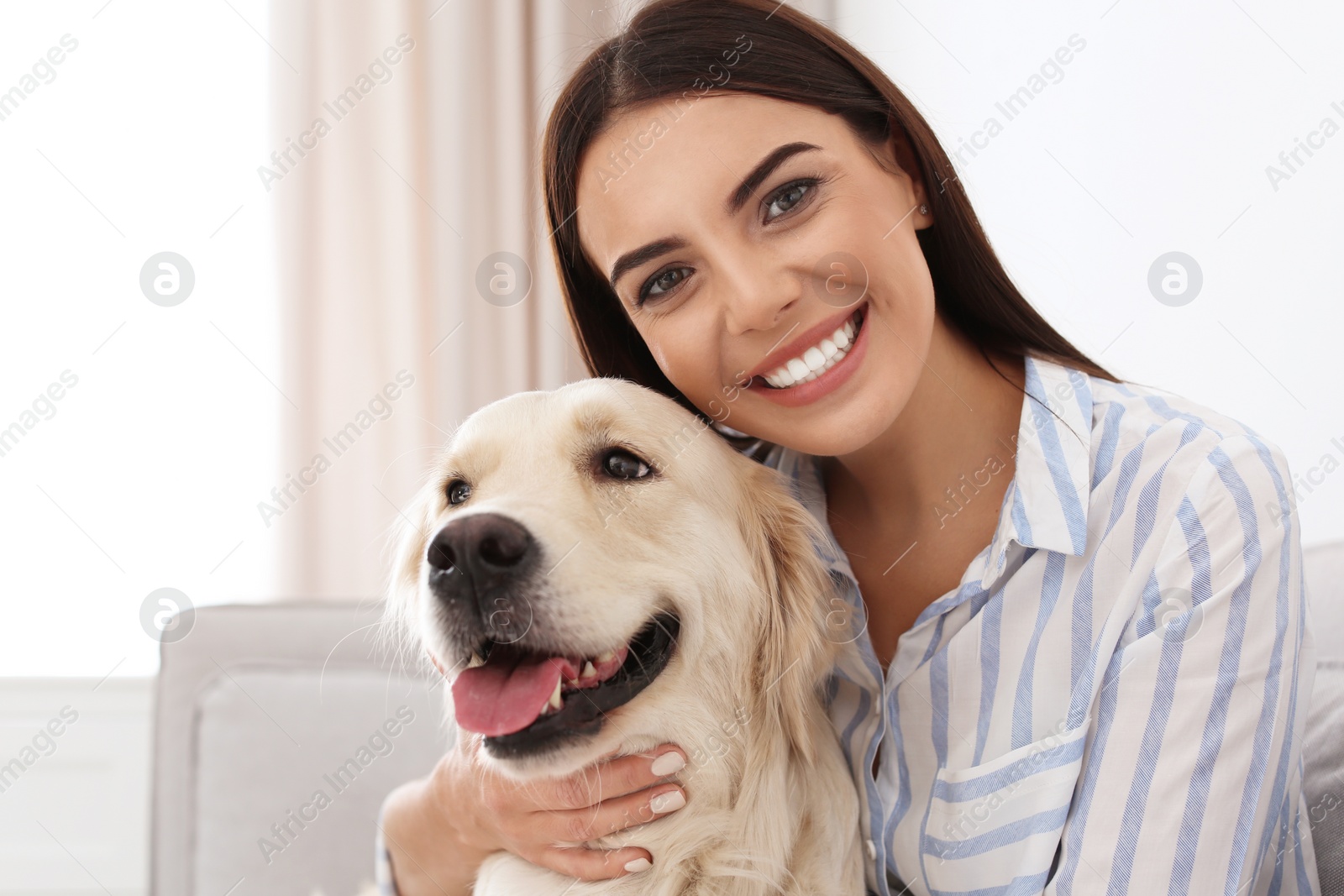 Photo of Young woman and her Golden Retriever dog in living room