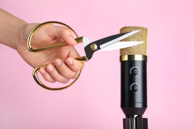 Photo of Woman making ASMR sounds with microphone and scissors on pink background, closeup