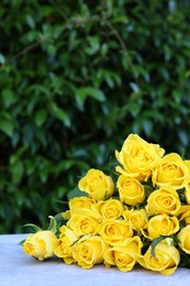 Beautiful bouquet of yellow roses on light table outdoors, space for text