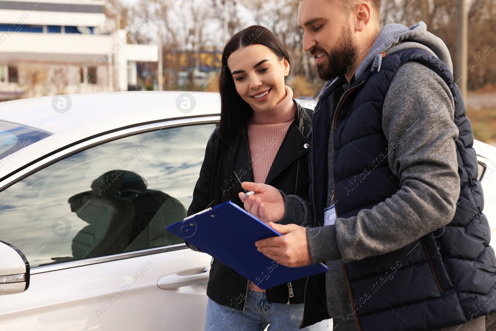 Photo of Young woman with instructor near car at driving school test track