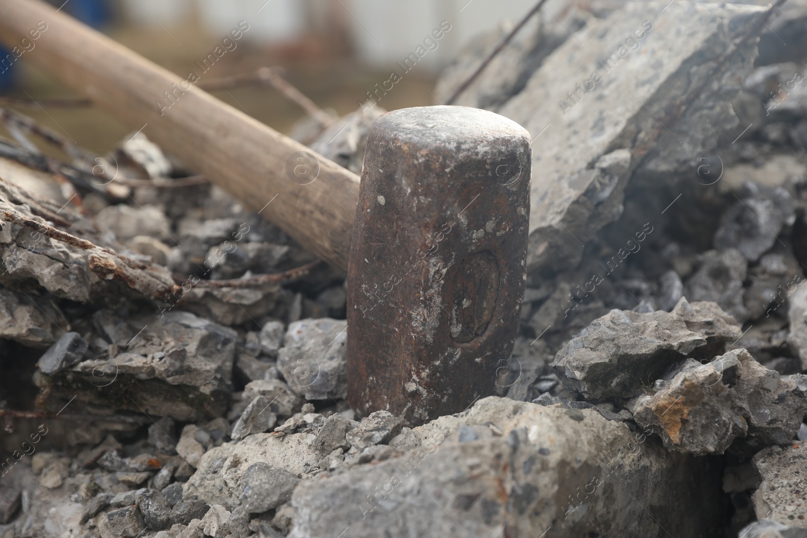 Photo of Sledgehammer on pile of broken stones outdoors, closeup