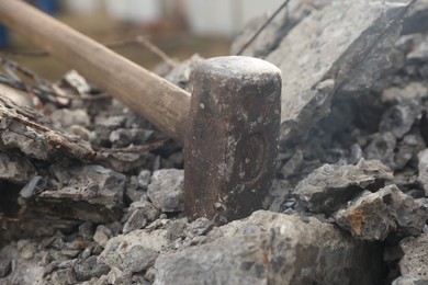 Photo of Sledgehammer on pile of broken stones outdoors, closeup