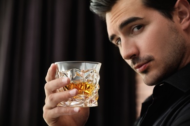 Young man with glass of whiskey indoors